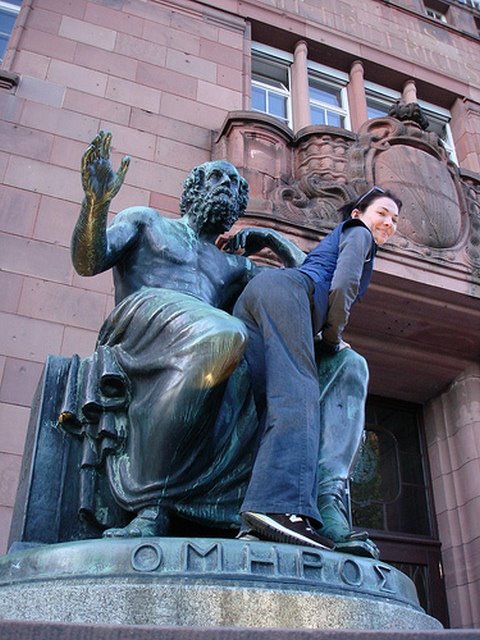 Girl positioned over the knee of a statue of Homer